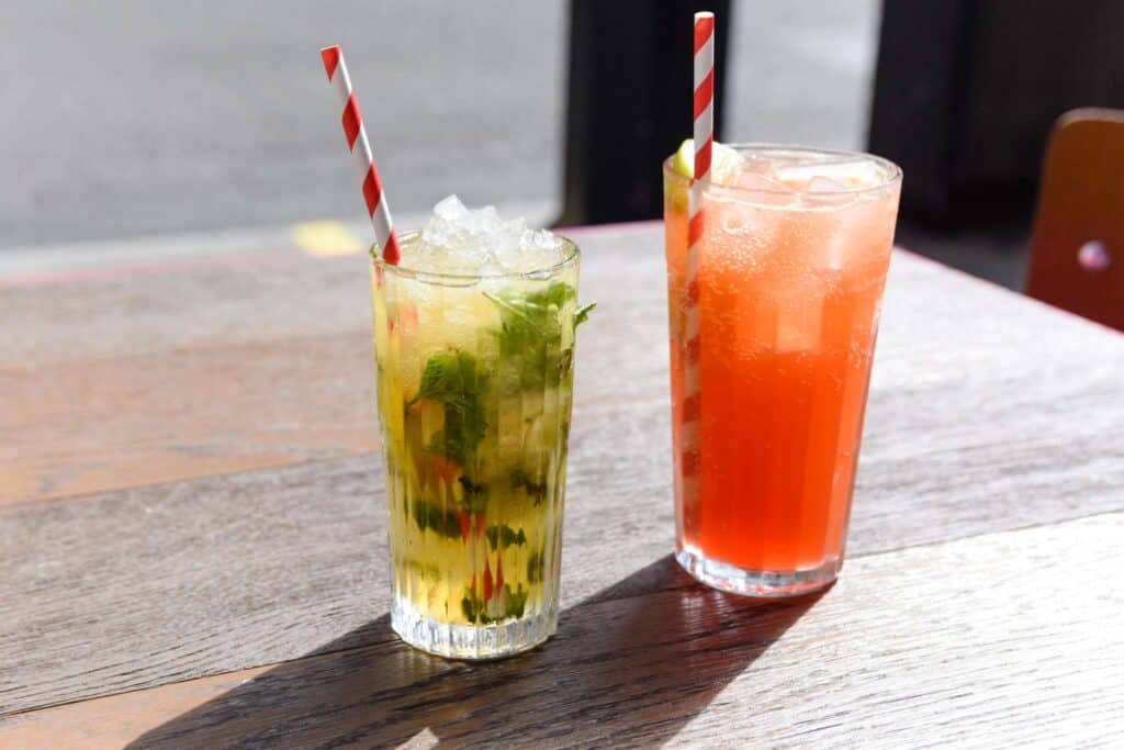 Two drinks sit on a table; the Wahaca passionfruit and hibiscus cooler, and mojito