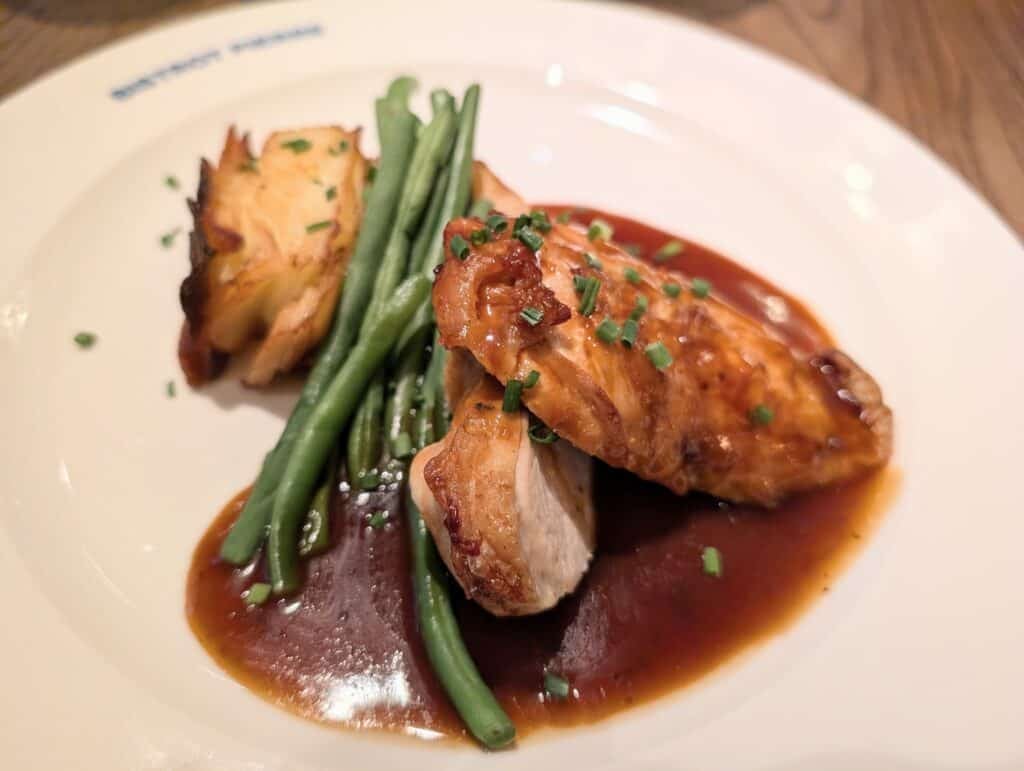 Chicken is served on a plate with green beans and potato